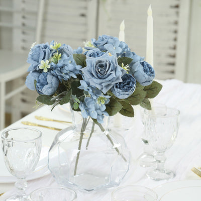 Blue floral arrangement in a clear vase on a dining table.
