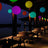Colorful hanging lanterns illuminate a serene outdoor dining area at night.