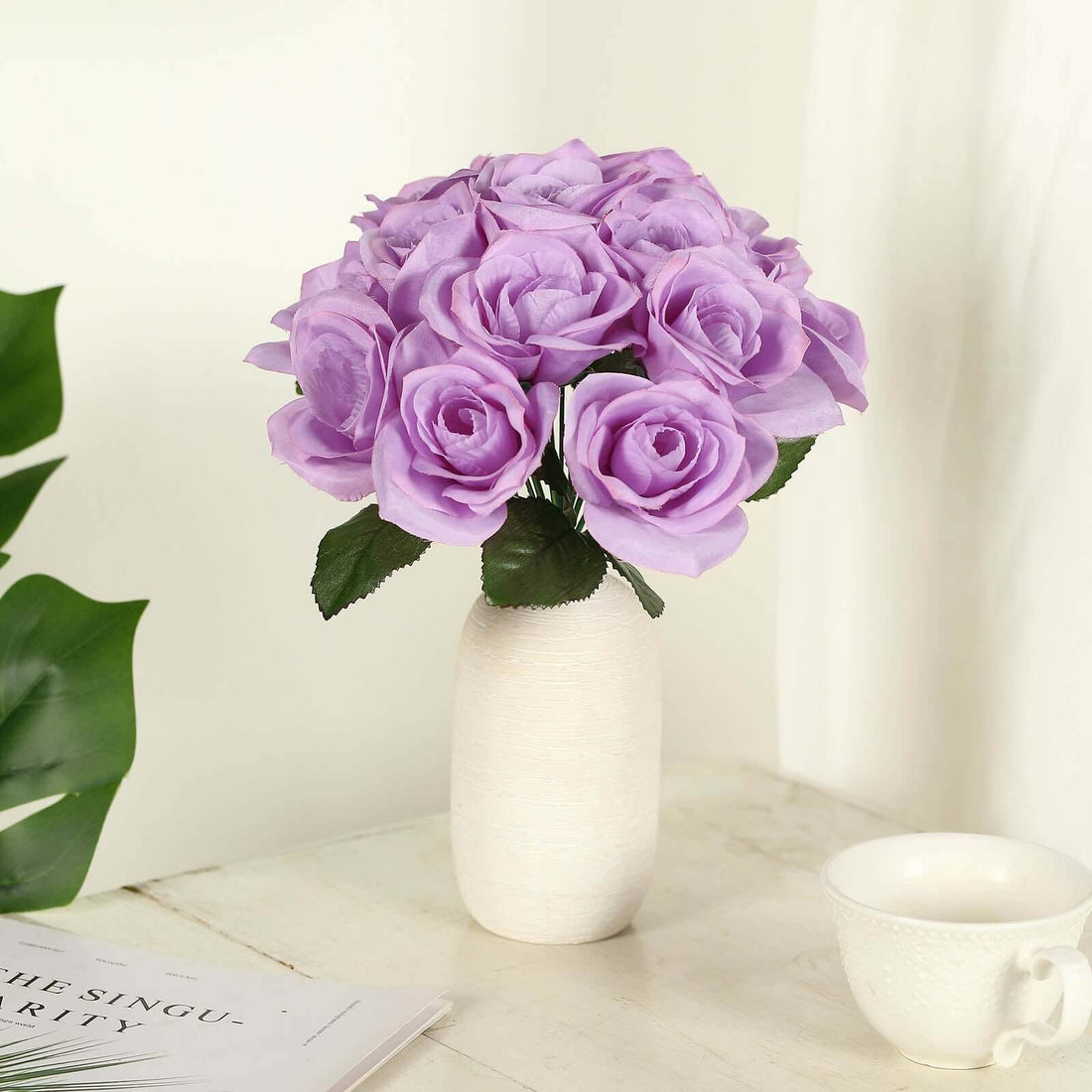 Purple artificial roses in a white vase on a table.