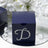 Navy blue gift box with rhinestone "D" design against floral backdrop.