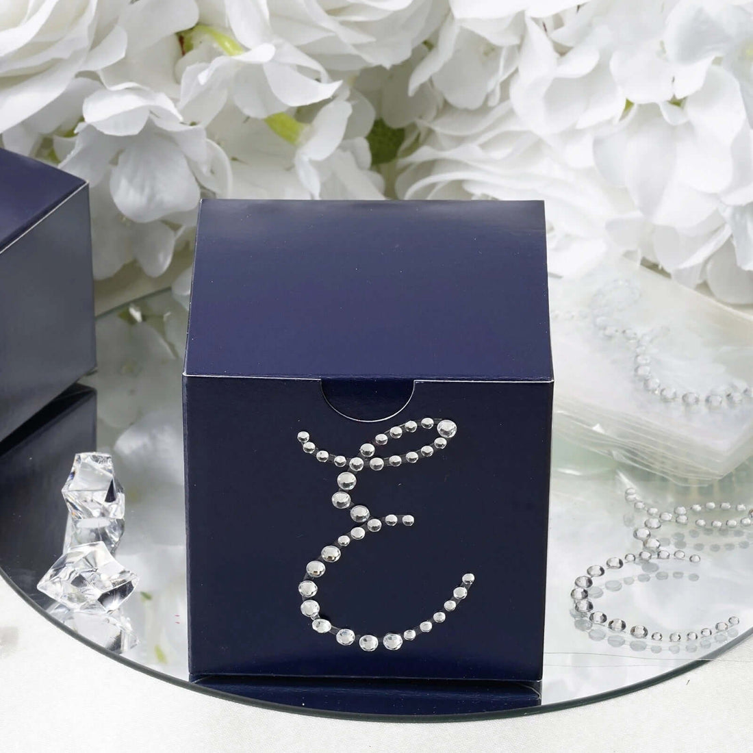 Navy blue gift box adorned with rhinestones on a reflective surface.
