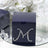 Navy blue gift box with rhinestone letter M design on a reflective surface.