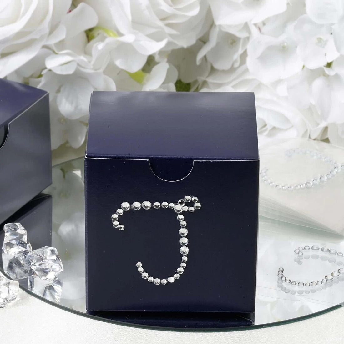 Navy gift box with rhinestone letter 'J' design on a reflective surface.