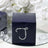 Navy gift box with rhinestone letter 'J' design on a reflective surface.