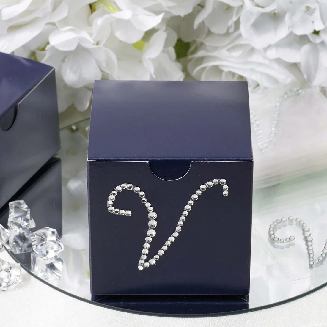 Navy box with rhinestone embellishment on a reflective surface.
