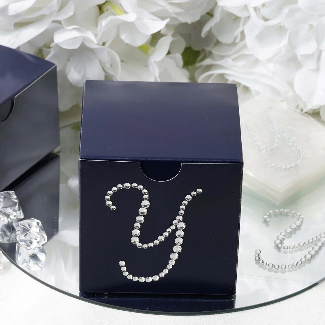 Navy gift box with rhinestone 'Y' design on a reflective surface.