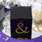 Black gift box adorned with yellow rhinestones on a reflective surface.