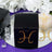 Black gift box adorned with rhinestones on a reflective surface.