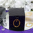 Black gift box with decorative golden swirl design on a reflective surface.