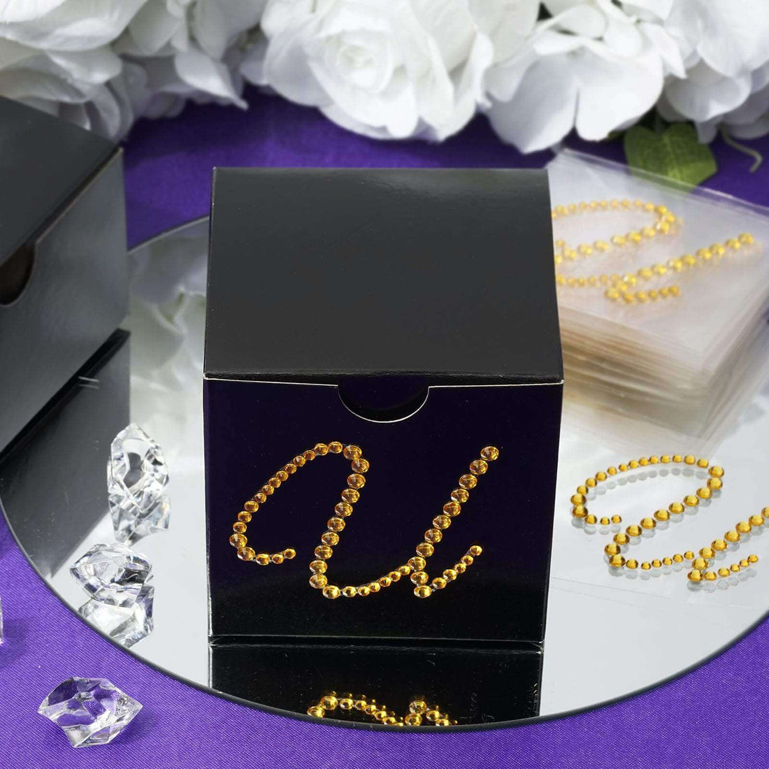 Black gift box adorned with gold rhinestones and decorative elements.