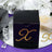 Black gift box with rhinestone "R" design on a mirrored surface.