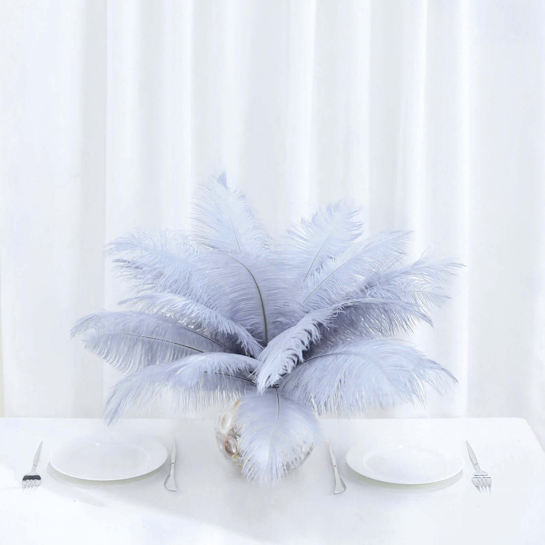 Silvery feather centerpiece in a clear vase on a table setting