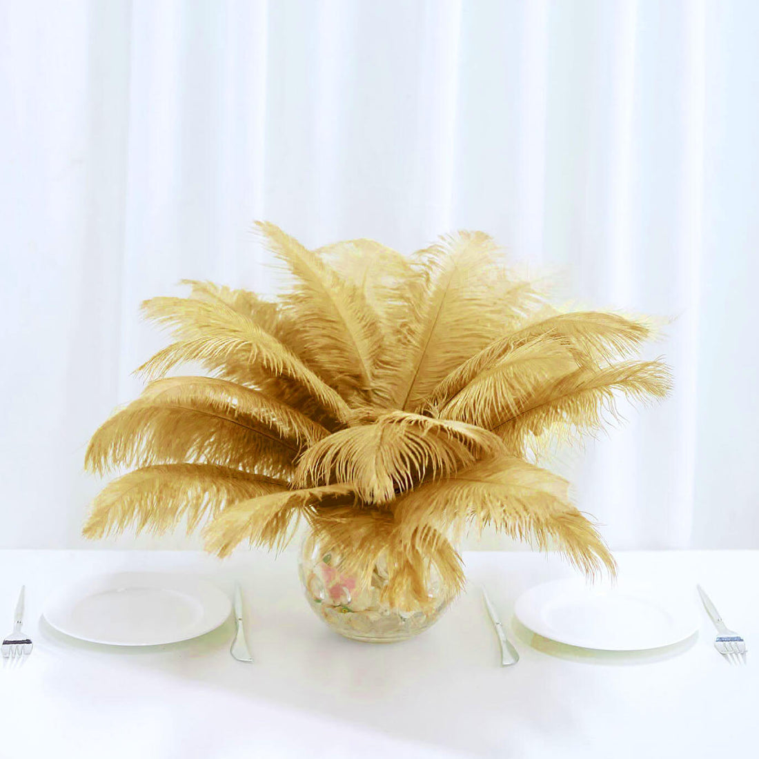 Gold feather centerpiece in a glass vase on a dining table.