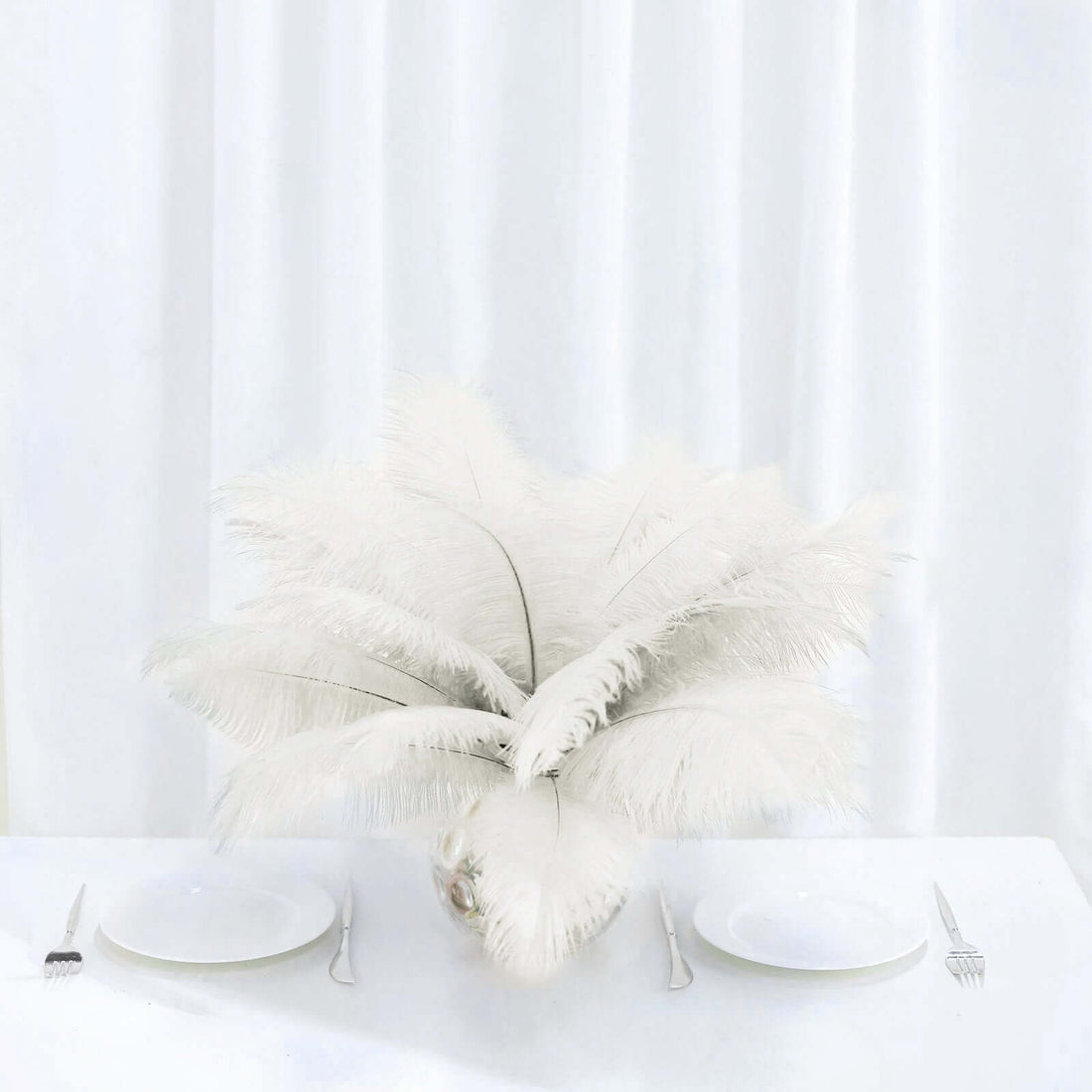 White feather centerpiece arrangement on a dining table.