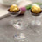 Clear glass dessert cups with iridescent finish on a textured surface.