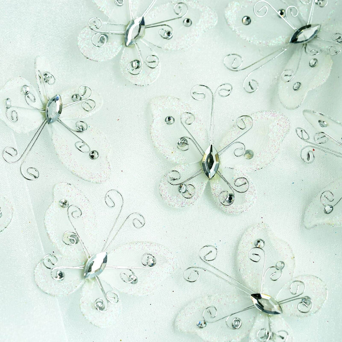 Decorative butterfly embellishments with silver accents on a light background.