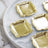 Set of ornate gold square trays on a marble surface.