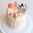 Elegant pink cake adorned with macarons and a silver crown on top.