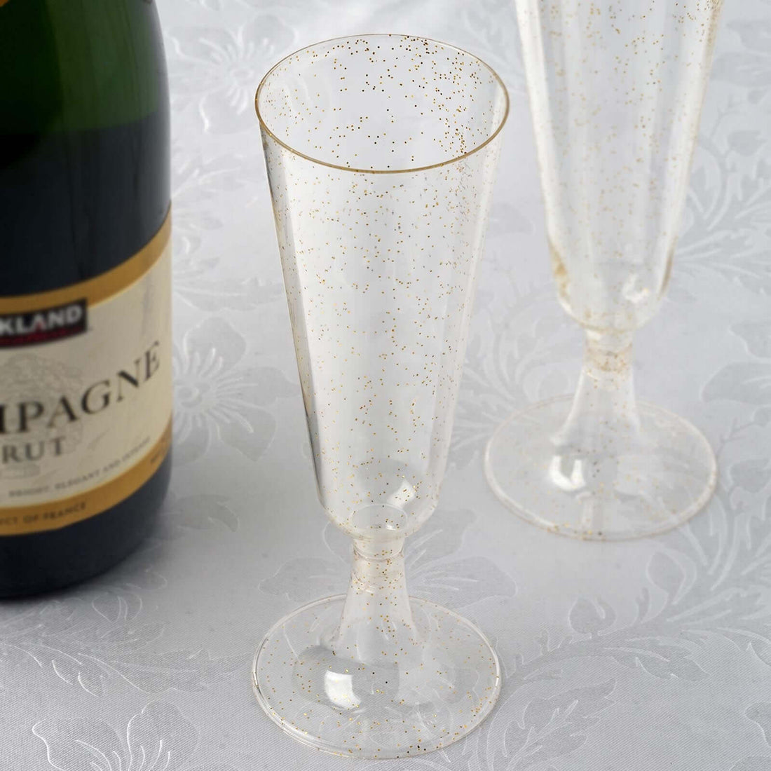Champagne flutes with gold speckles next to a bottle of champagne.
