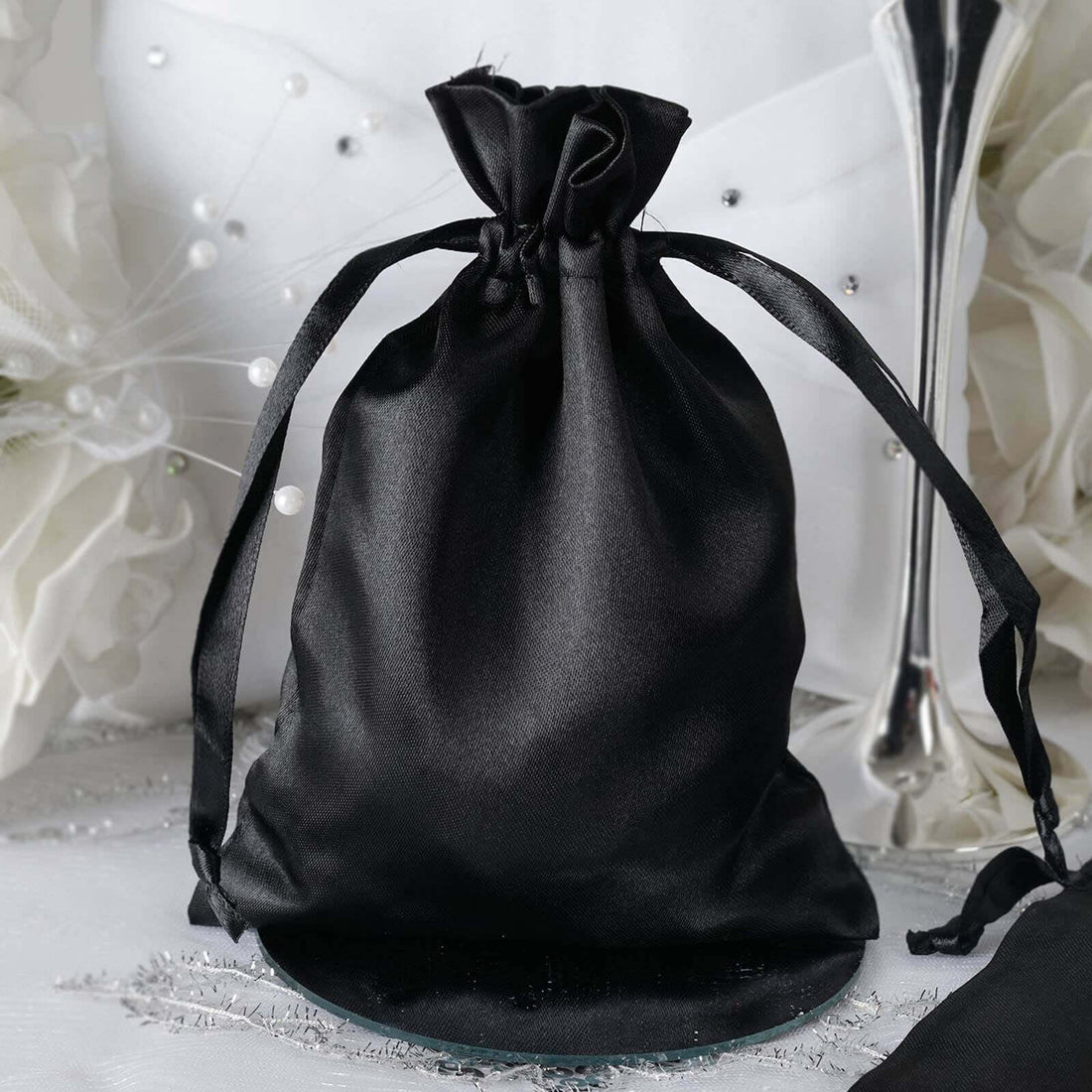 Black satin drawstring bag on a decorative table.