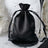 Black satin drawstring bag on a decorative table.