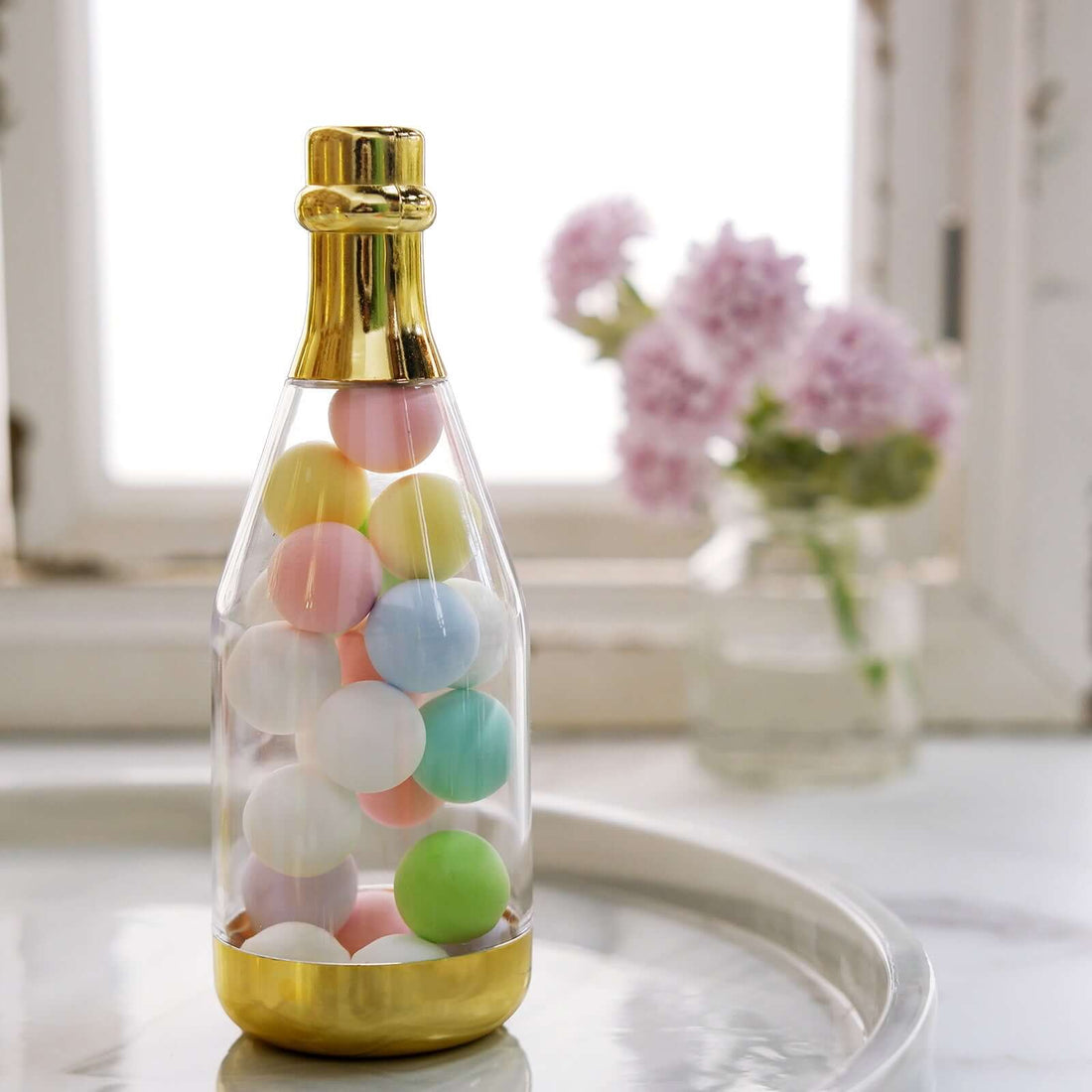 Colorful decorative balls in a clear bottle with a gold base.