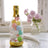 Colorful decorative balls in a clear bottle with a gold base.