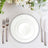 Elegant white dinner plates stacked with silver cutlery on a table setting.