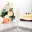 Elegant champagne flute with sparkling drink, surrounded by flowers and cake.