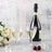 Champagne glasses with bottle and cherries on a table, surrounded by flowers.