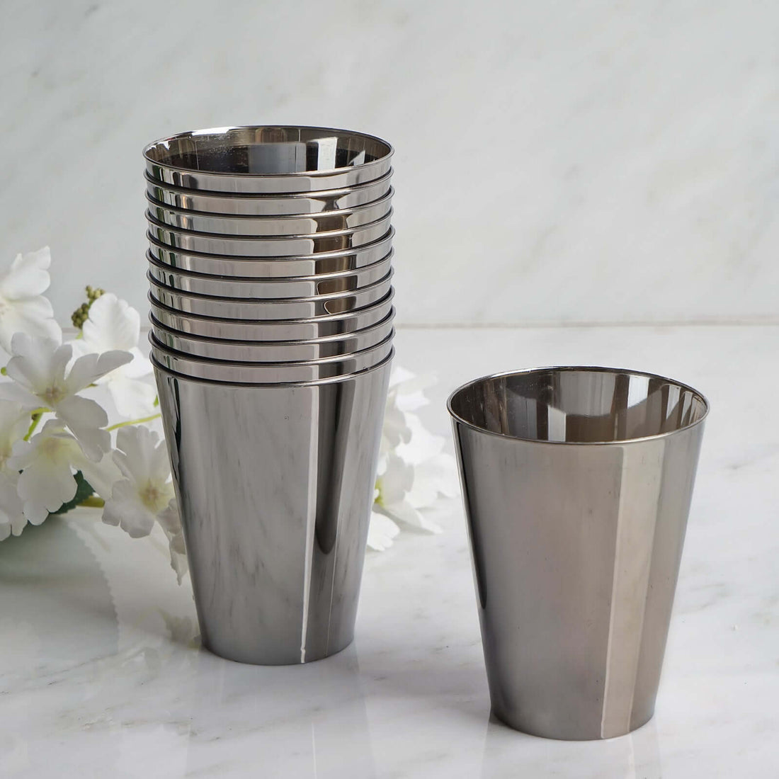 Set of stainless steel cups stacked with one upright on a marble surface.