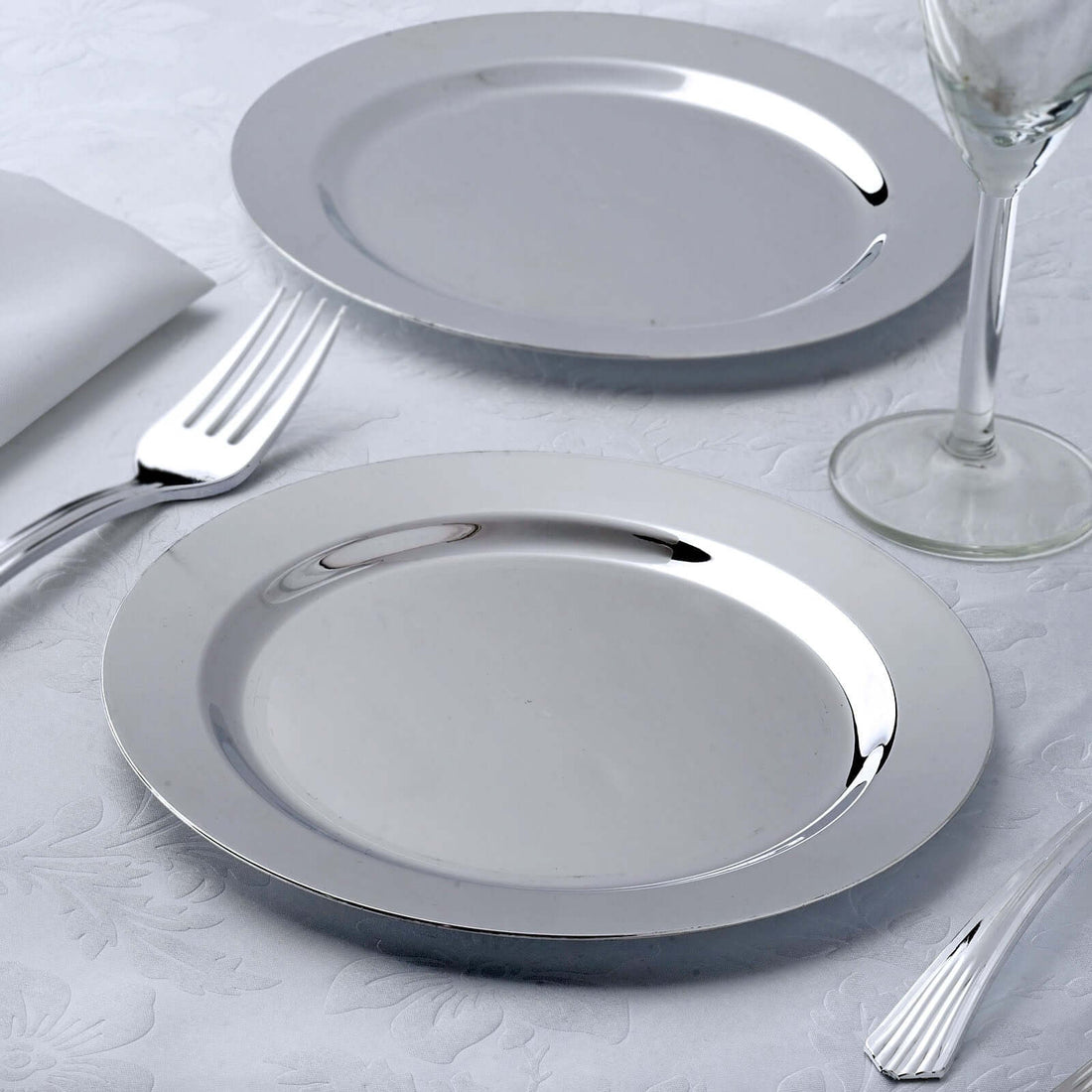 Polished silver serving plates on an elegant table setting.