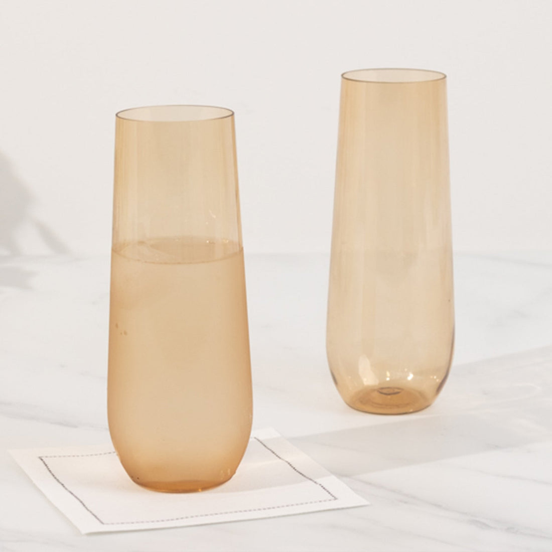 Two elegant amber tumblers on a white surface.