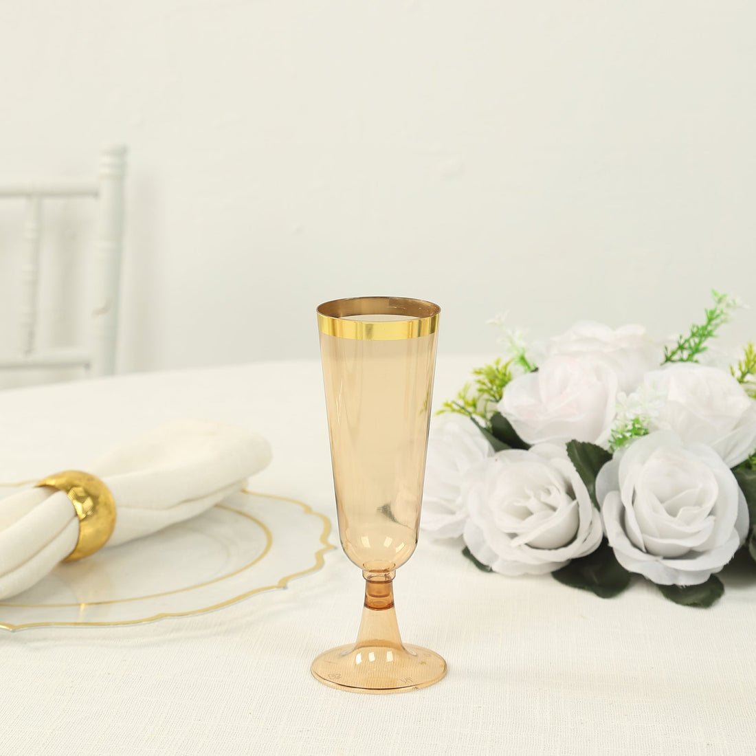 Elegant gold-rimmed champagne flute on a table with white roses