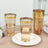 Gold-rimmed glass tumblers on a plate with water.