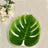 Monstera leaf decoration on a table with flowers and a candle.