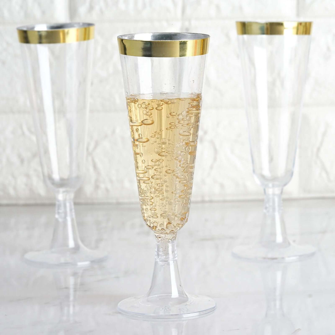 Elegant clear champagne flutes with gold rims, filled with bubbly drink.