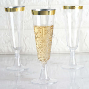 Elegant clear champagne flutes with gold rims, filled with bubbly drink.