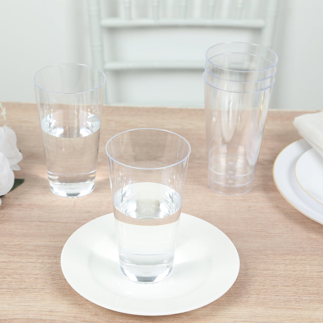 Clear plastic glasses on a wooden table with water inside.