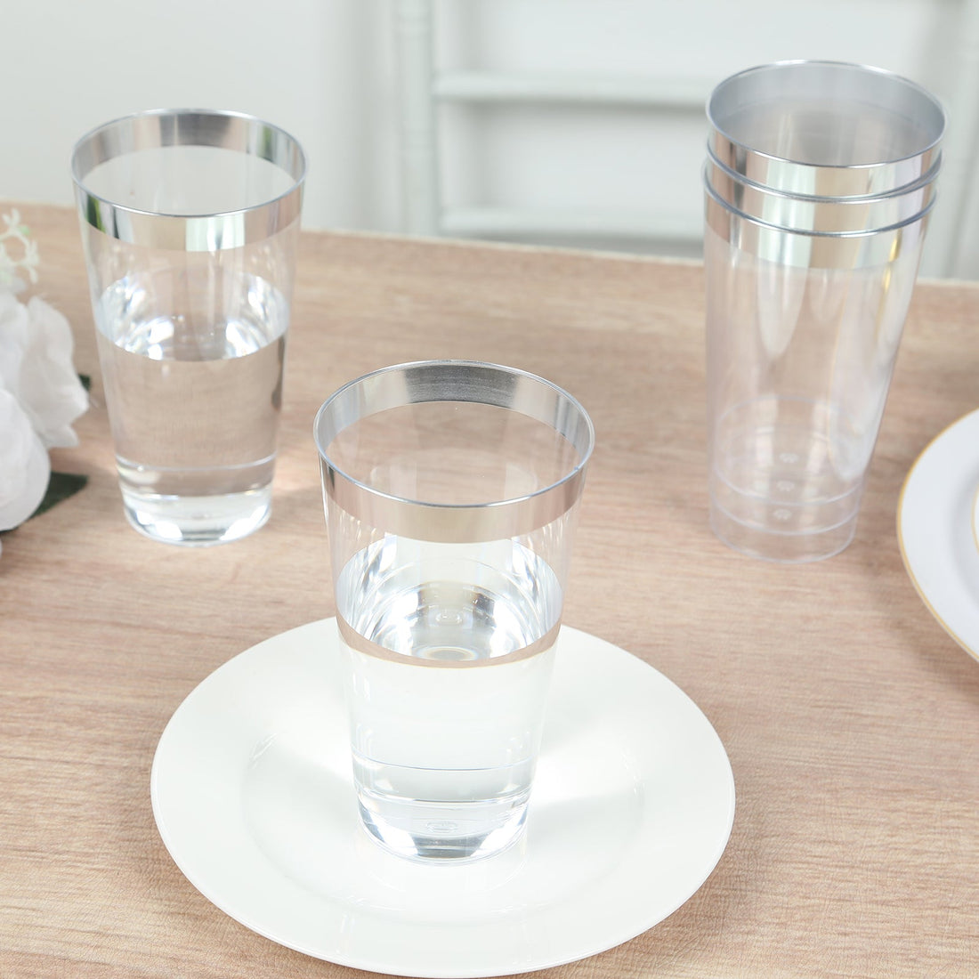 Clear plastic cups with silver rims on a wooden table setting.