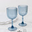 Two blue ribbed glass goblets on a marble table.