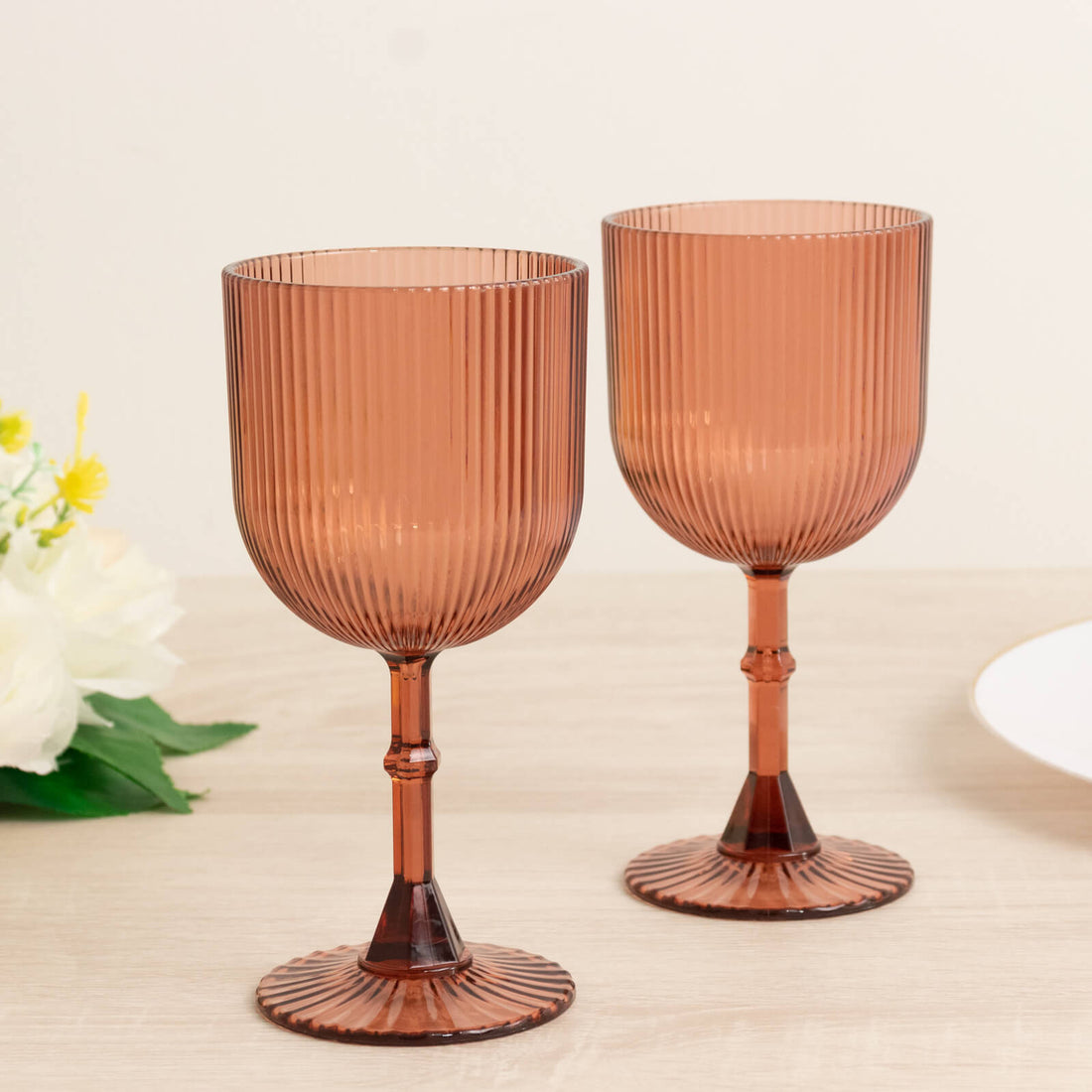 Set of two ribbed amber glass goblets on a light wooden table.