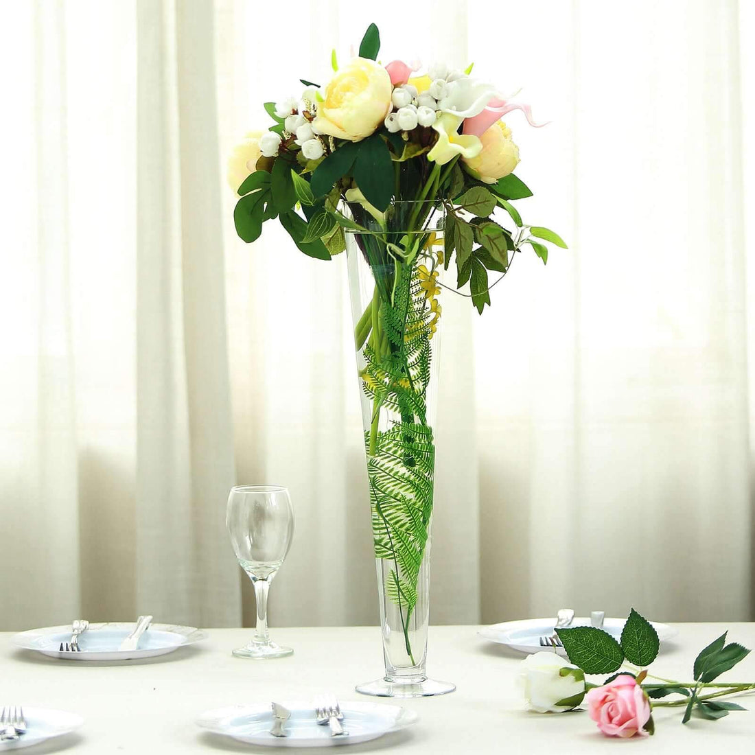 Tall floral arrangement in a clear vase on a dining table.