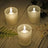 Frosted glass candles with flickering flames on a wooden surface.