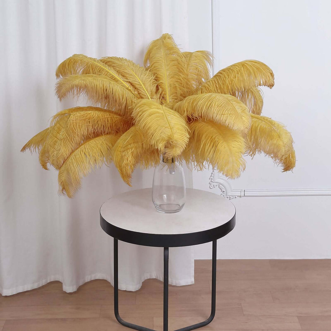 Yellow feather bouquet in a glass vase on a round table.