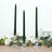 Three twisted green candles in clear glass holders with floral accents.