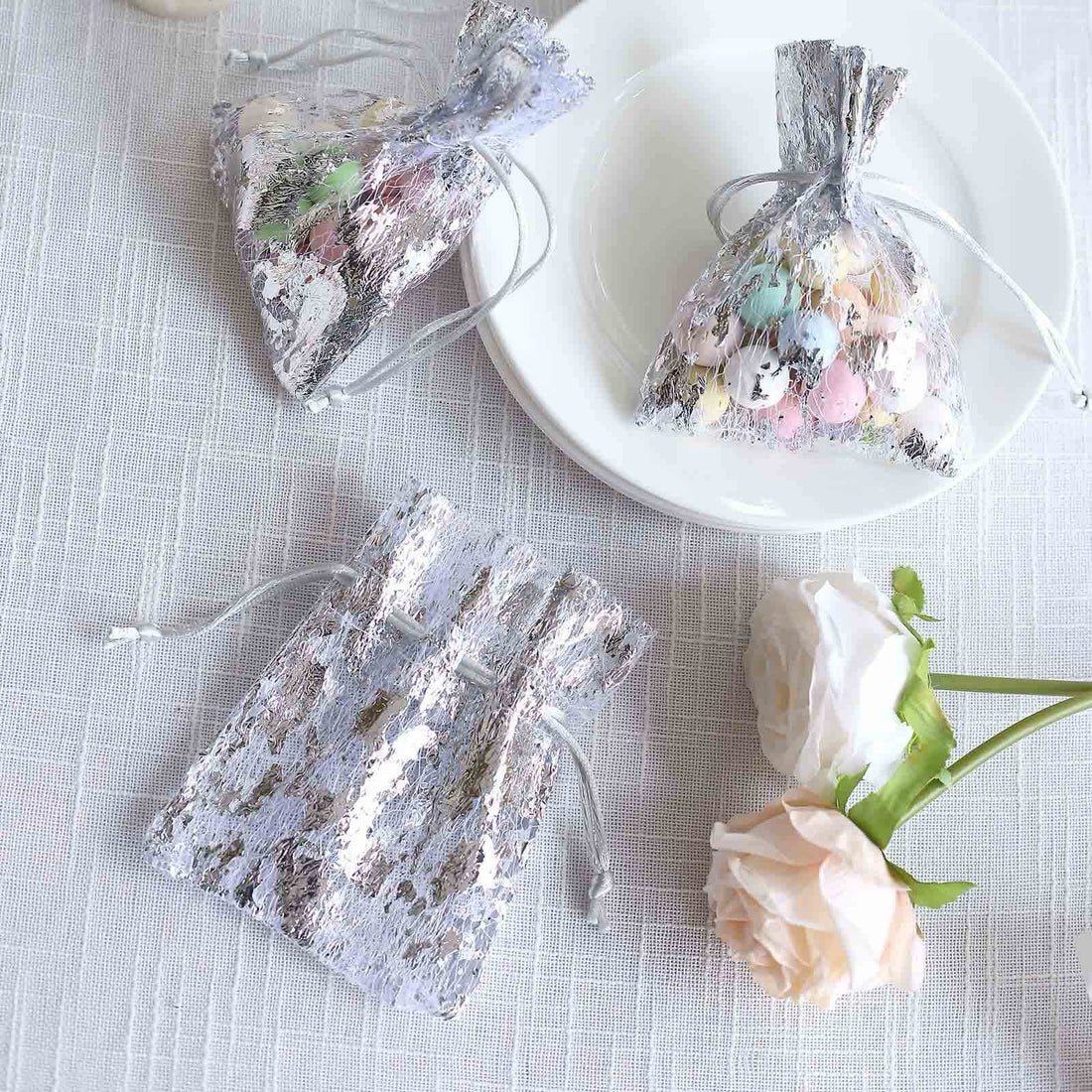Silver gift bags filled with colorful candies on a white table.