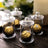 Glass jars with gold foil chocolates inside, elegantly displayed on a wooden table.