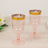 Pink plastic champagne flutes with gold rims on a wooden surface.