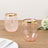 Pink and gold rimmed drinking glasses on a wooden table.